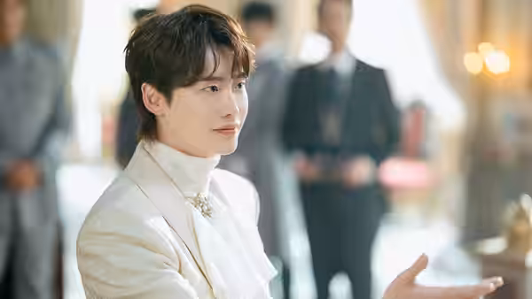 Heinrey (Lee Jong-suk) gestures in a white suit at a formal gathering