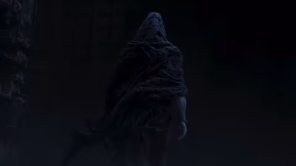 A hooded figure walks through a dim stone passage