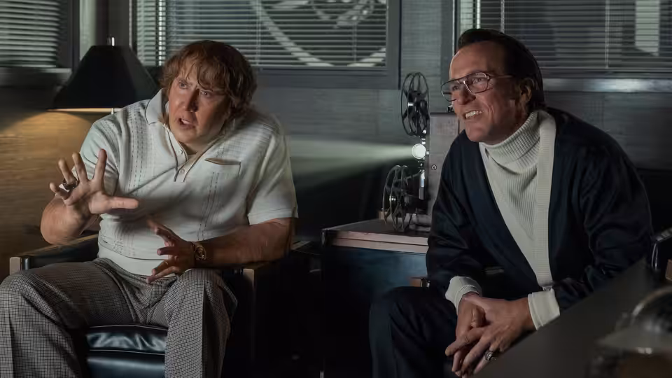 John Madden (Nicolas Cage) talks with Al Davis (Christian Bale) in an office