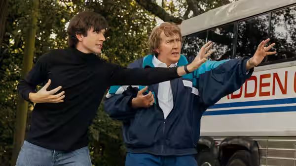 John Madden (Nicolas Cage) and a young man gesture beside a team bus