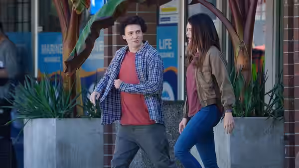 Sam Bankman-Fried (Anthony Boyle) walking beside Caroline Ellison (Julia Garner) past planters