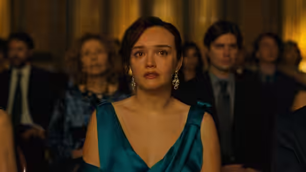 Clementine Balfour (Olivia Cooke) sits in a teal dress among formally dressed guests