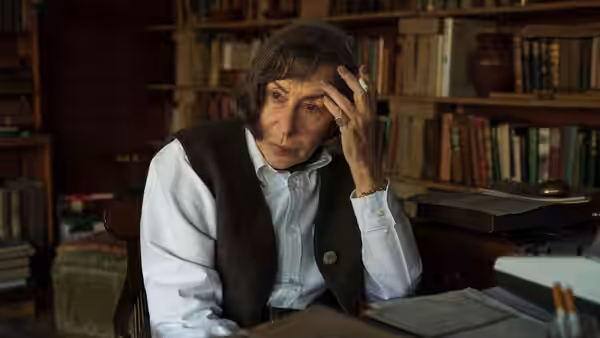 Patricia Highsmith (Helen Mirren) sits at a library desk, pressing her fingers to her temple
