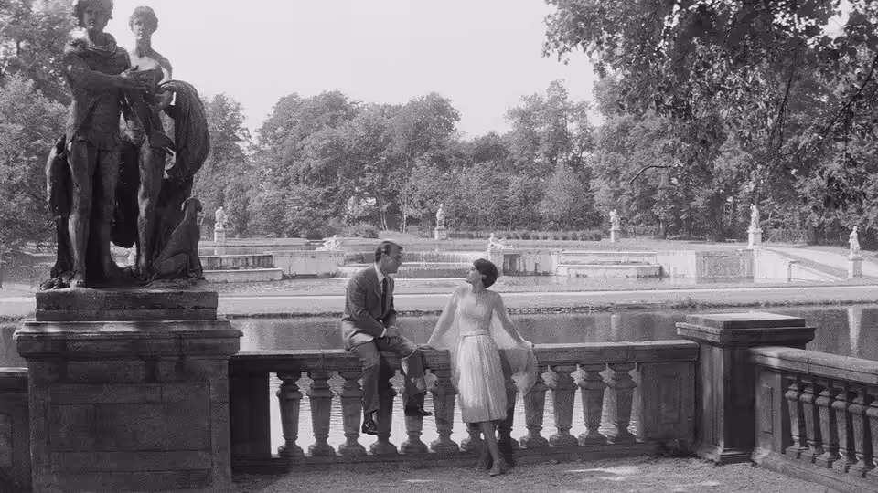 X (Giorgio Albertazzi) and A (Delphine Seyrig) stand beside a statue on a hotel terrace