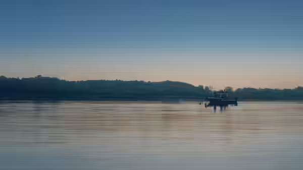 A small boat floating on a calm river at dusk