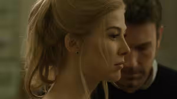 Amy Dunne (Rosamund Pike) in profile with Nick Dunne (Ben Affleck) behind