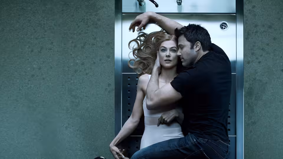 Amy Dunne (Rosamund Pike) embraced by Nick Dunne (Ben Affleck) in an elevator