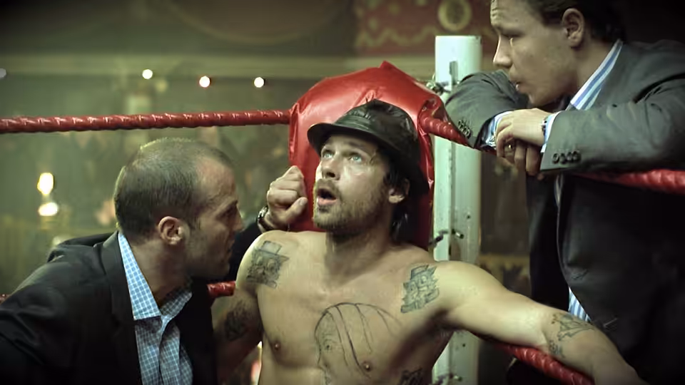 Mickey O'Neil (Brad Pitt) in a boxing ring with two suited men