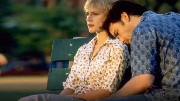 Rob (John Cusack) and Laura (Iben Hjejle) on a park bench at dusk
