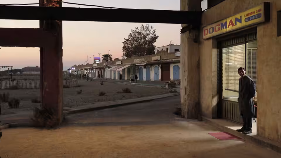 Marcello (Marcello Fonte) stands outside the Dogman grooming shop in a deserted coastal district