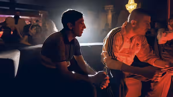 Marcello (Marcello Fonte) and Simoncino (Edoardo Pesce) sit together in a smoky nightclub