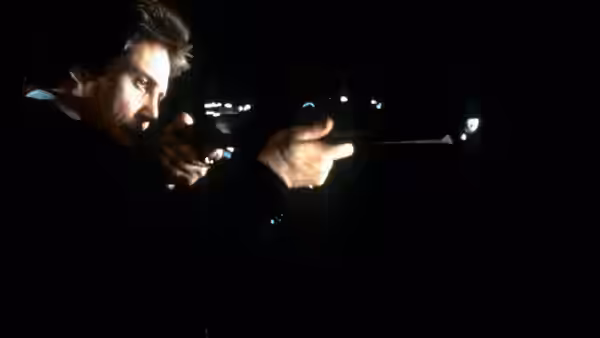 Johnny Smith (Christopher Walken) aiming a rifle into the night from darkness