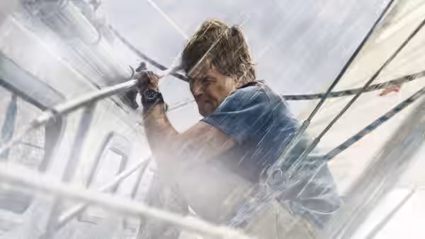 Our Man (Robert Redford) braces himself against a rail on the storm-tossed boat
