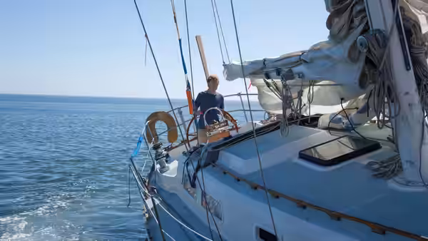 Our Man (Robert Redford) steers his sailboat across calm open water