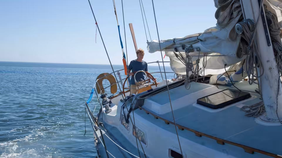 Our Man (Robert Redford) steers his sailboat across calm open water
