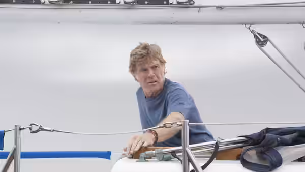 Our Man (Robert Redford) reaches toward the sailboat's deck rail
