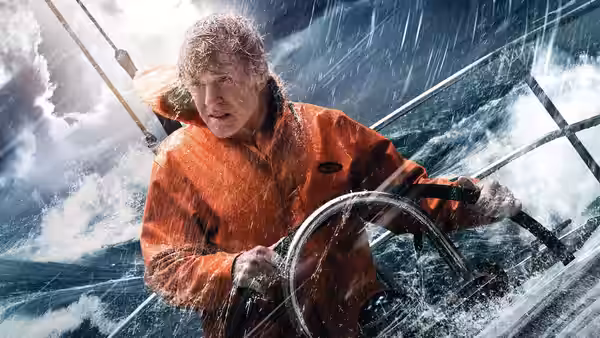 Our Man (Robert Redford) grips the sailboat's wheel as waves crash around him