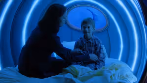 Monica (Frances O'Connor) talks to Martin (Jake Thomas) inside a glowing blue circular bed