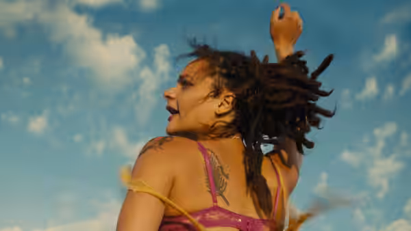 Star (Sasha Lane) with arm raised and hair blowing in the wind