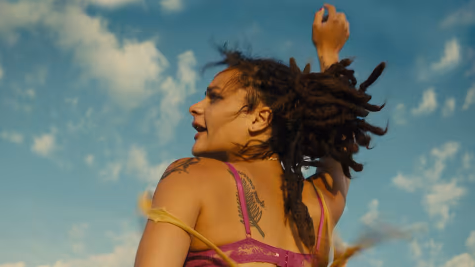 Star (Sasha Lane) with arm raised and hair blowing in the wind