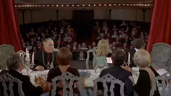 Monsignor Dufour (Julien Bertheau) at a table on a theater stage