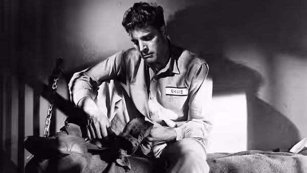 'Swede' Andersen (Burt Lancaster), wearing a prison uniform, sits on a bunk