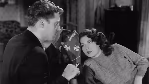 Jim Reardon (Edmond O'Brien) speaks with Kitty Collins (Ava Gardner) indoors