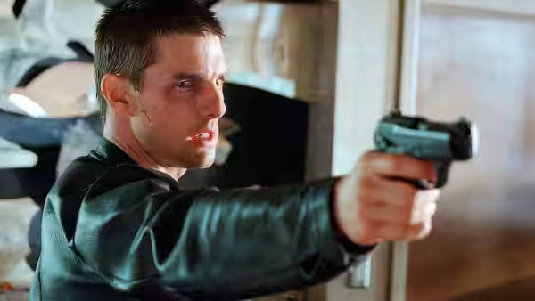 Chief John Anderton (Tom Cruise) aiming a pistol to his right