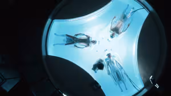 Four people floating motionless inside a circular illuminated water tank