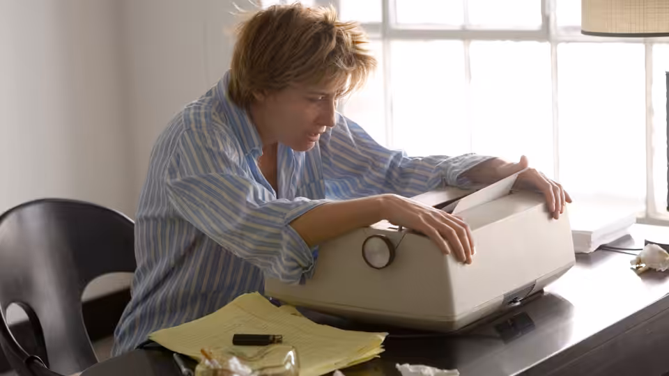 Karen Eiffel (Emma Thompson) leaning over a typewriter on a desk