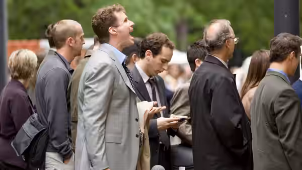 Harold Crick (Will Ferrell) standing among a crowd and looking upwards