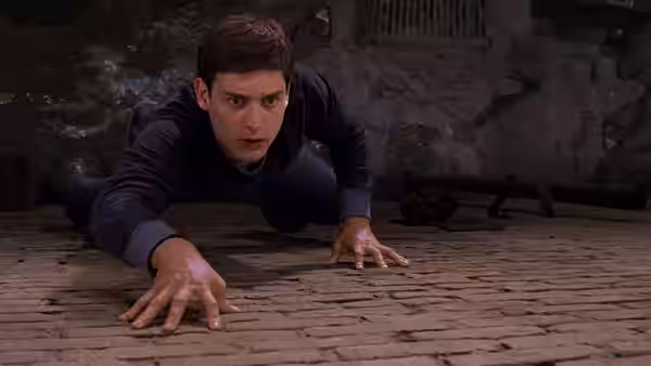 Peter Parker (Tobey Maguire) crawling on all fours across a brick floor