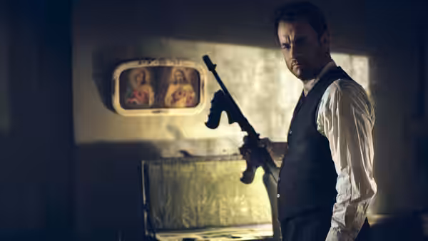 Michael Sullivan (Tom Hanks) holding a Thompson submachine gun beside an open case