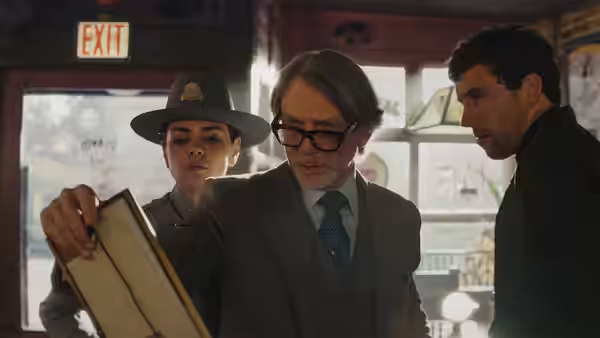 Fr. Jud Duplenticy (Josh O'Connor) beside a sheriff examining a document