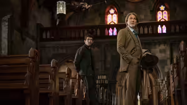 Benoit Blanc (Daniel Craig) and Fr. Jud Duplenticy (Josh O'Connor) inside a church