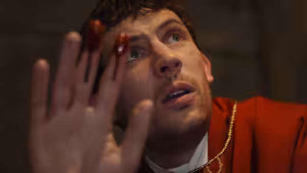 Fr. Jud Duplenticy (Josh O'Connor) raising a bloody hand and looking upward