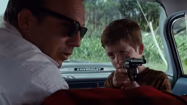 Phillip points a toy gun at Butch Haynes inside a Chevrolet