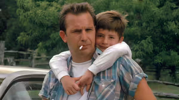 Butch Haynes (Kevin Costner) carries Phillip on his back beside a car
