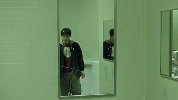A young man standing in a bathroom looking at his reflection in the mirror