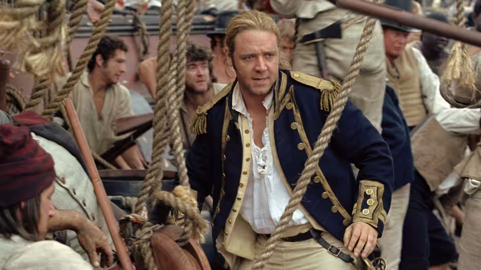 Captain Jack Aubrey (Russell Crowe) standing on the ship's deck among sailors