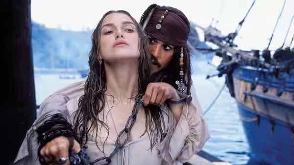 Jack Sparrow (Johnny Depp) holding Elizabeth Swann (Keira Knightley) by a chain on a pier