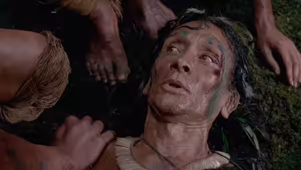 An injured man lies on the forest floor as others tend to him