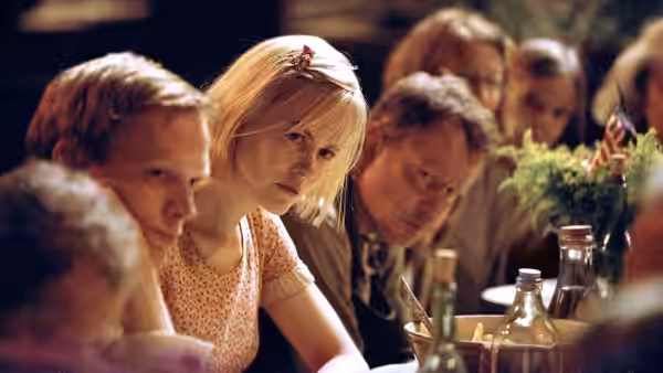 A blonde woman sits at a table with men during a group meal