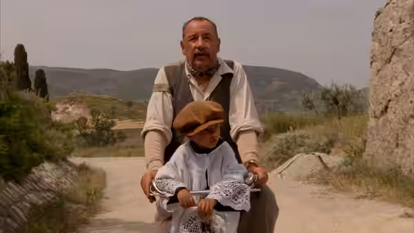 Alfredo riding a bicycle with young Totò on the handlebars