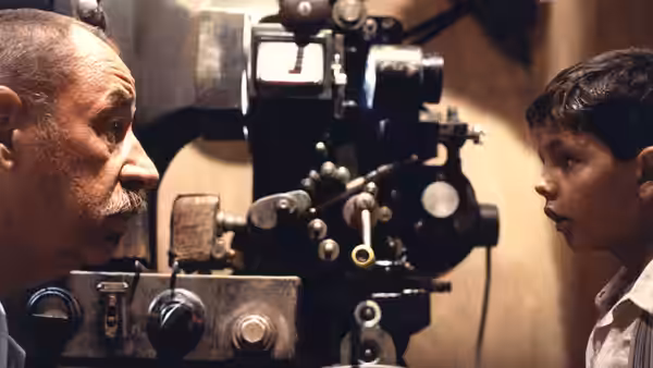 Alfredo and young Totò face each other beside a film projector