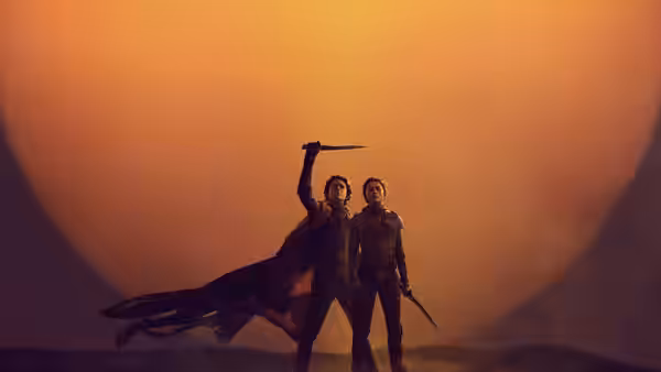 Paul Atreides (Timothée Chalamet) raising a sword beside Chani (Zendaya) before the sun