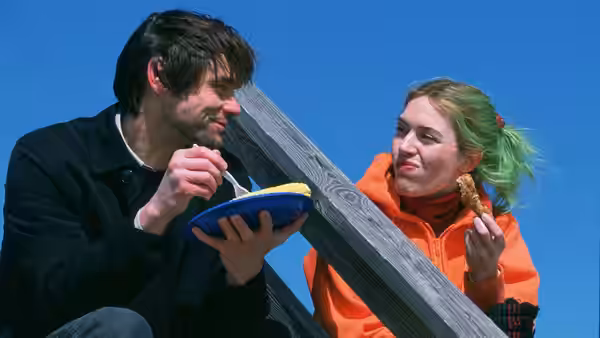 Joel (Jim Carrey) eating from a bowl beside Clementine (Kate Winslet) outdoors