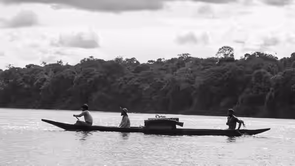 Three travelers in a canoe on a river with tree-lined shore