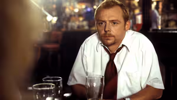 Shaun (Simon Pegg) seated at a pub table with empty glasses in front