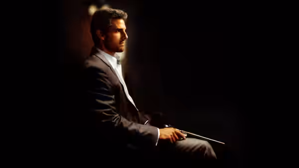 Vincent (Tom Cruise) seated with a gun resting across his lap in shadow